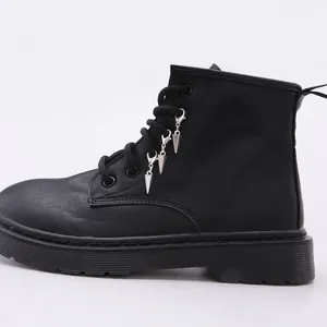 Detalle de botas militares negras mates con colgantes metálicos plateados en los cordones