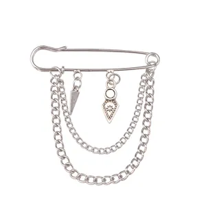 Detail of silver safety pin brooch with double chains and geometric sunburst pendants