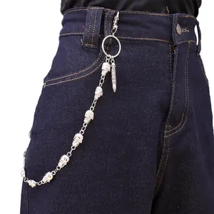 Detail van zilveren punk broekketting met schedels en kogelhanger op een denim jeans