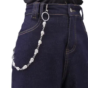 Detail of silver skull chain accessory styled on blue denim jeans for punk hip-hop look