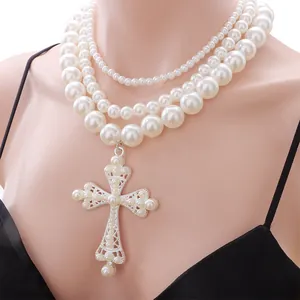 Dettaglio collana di perle bianche multistrato con pendente a croce in argento ornato
