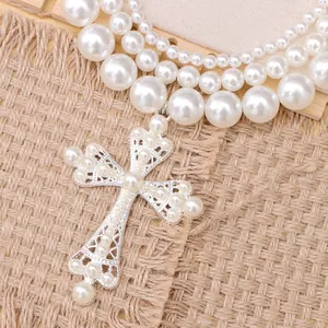 Dettaglio collana di perle a più strati con grande pendente a croce in argento vintage