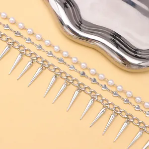 Punk layered necklace with pearls, heart charms, and silver spikes on a pink background