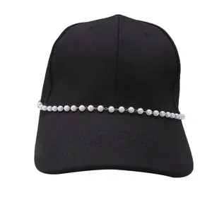 Detail of a black cotton baseball cap featuring stylish white pearl chain decor on the brim