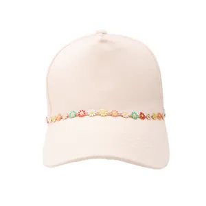 Détail d'une casquette avec chaîne de marguerites colorées et pendentifs en strass
