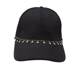 Détail de la casquette noire en coton avec chaîne dorée et pendentifs de fleurs de marguerite