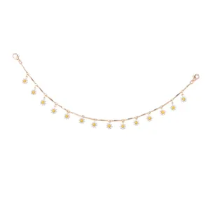 Détail de chaîne dorée avec pendentifs marguerites blanches et fermoirs pour chapeau