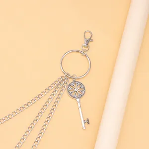 Detail einer silbernen mehrlagigen Metallhose-Kette mit Vintage-Schlüsselanhänger und Karabiner