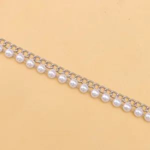 Dettaglio macro di elegante catena per borsa in metallo argento con perle finte
