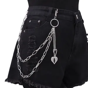Détail de la chaîne de pantalon double en métal avec pendentif cœur plume sur denim noir