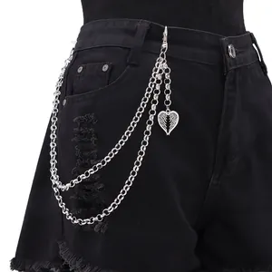 Détail d'une chaîne de pantalon argentée multicouche avec pendentif cœur ailé sur un jean