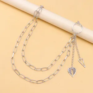 Détail d'une chaîne argentée double couche avec pendentifs cœur et aile sur tube crème