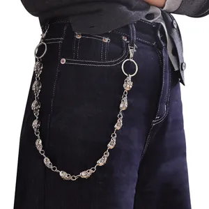 Détail d'une chaîne de pantalon tête de mort en métal argenté sur un jean en denim