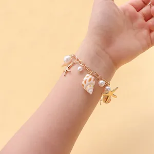 Detail of beach style bracelet with golden starfish, faux pearl, and natural shell charms