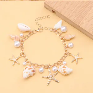 Detail of bohemian gold bracelet with sea shell, starfish charms and faux pearls