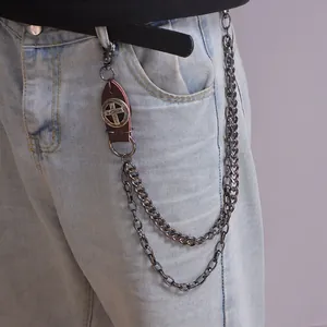 Detail of punk style metal wallet chain with leather cross patch on denim jeans