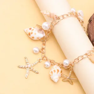 Detail of beach bracelet with golden starfish, natural seashells, and pearl charms