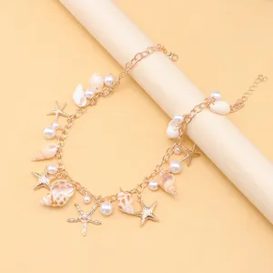 Detail view of gold alloy anklet featuring starfish, seashell, and imitation pearl charms