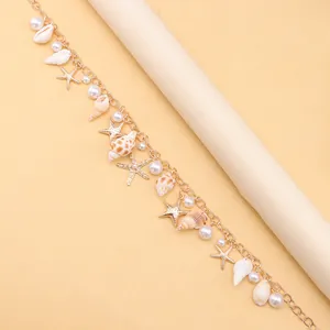 Macro view of gold chain bracelet with sea shells, pearls and starfish charms