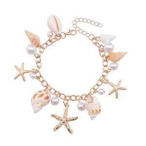 Detail of bohemian gold charm bracelet with seashells, starfish and pearls for summer