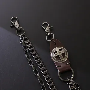 Detail of dark metal punk trousers chain featuring a vintage leather cross emblem