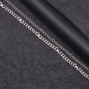 Detail of silver thorn barbed wire chain and cuban link with punk metal texture