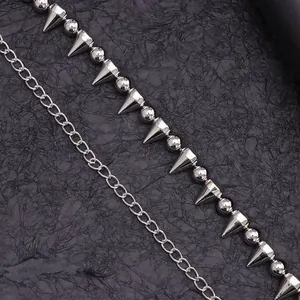 Dettaglio catena a sfere d'argento con rivetti punk appuntiti su sfondo scuro