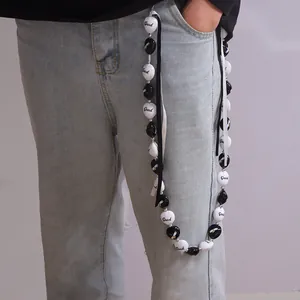 Détail d'une chaîne de pantalon style urbain avec perles Grad et rubans noir et blanc