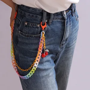 Detail der mehrlagigen Acryl-Hosenkette mit Regenbogenringen und Kirschanhängern an Jeans