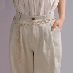 Detailed view of fashionable gold alloy ring waist chain styled on light colored trousers