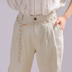 Detail of gold metal ring chain belt on model showing adjustable clasp and links