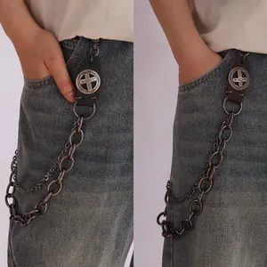 Detail of vintage metal trousers chain with brown leather cross and fish charms on jeans