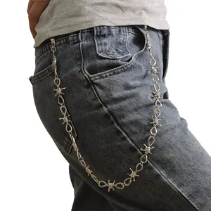Dettaglio della catena da vita in filo spinato argento con moschettoni sui jeans