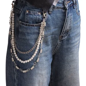 Cadena de pantalón multicapa de metal plateado con perlas blancas sobre vaqueros azules