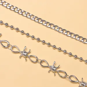 Close-up of three layered silver hip-hop waist chains including barbed wire and curb styles