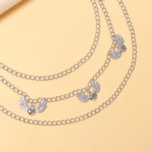 Detail of silver multi-layer waist chain with winged heart pendants on a neutral surface