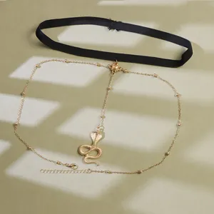 Detail of black elastic leg chain with golden cobra pendant and adjustable metal link chain