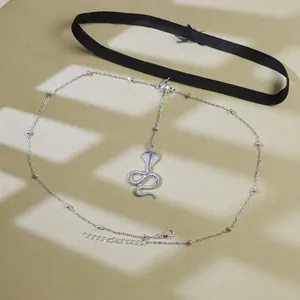 Close-up of black elastic leg chain with a silver cobra pendant and metallic beads