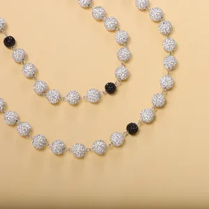 Vue macro de perles boules serties de cristaux sur une chaîne de corps argentée