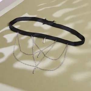 Detail view of multi-layer silver chains and metal charms on a black elastic leg chain