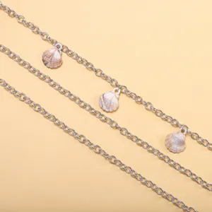 Détail d'une chaîne de pantalon multicouche argentée avec pendentifs coquillage naturel