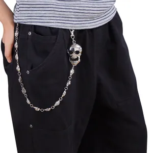 Détail d'une chaîne punk à crânes argentée avec grand pendentif sur un jean