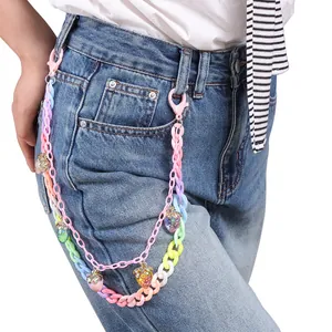 Détail d'une chaîne de taille double couche en acrylique avec pendentifs fraises sur jean