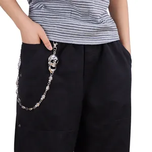 Gros plan d'une chaîne de pantalon punk argentée avec pendentif tête de mort sur pantalon noir