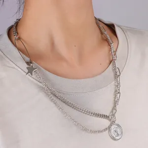 Dettaglio della collana a catena argentata a strati con spilla e ciondoli a moneta