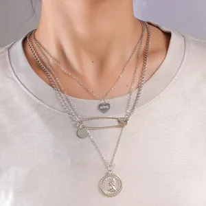 Collana a tre strati d'argento con ciondolo a cuore, spilla da balia e moneta su modella