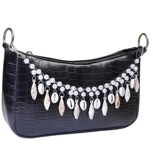 Close-up of black faux crocodile texture bag with decorative pearl and seashell charms