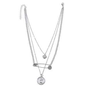 Dettaglio della collana argentata a strati con pendente a cuore, spilla e moneta