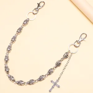 Detail of hip hop pants chain with silver skull links and a cross pendant charm