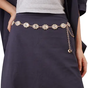 Detailed macro view of golden sunflower waist chain with crystal inlay on purple fabric